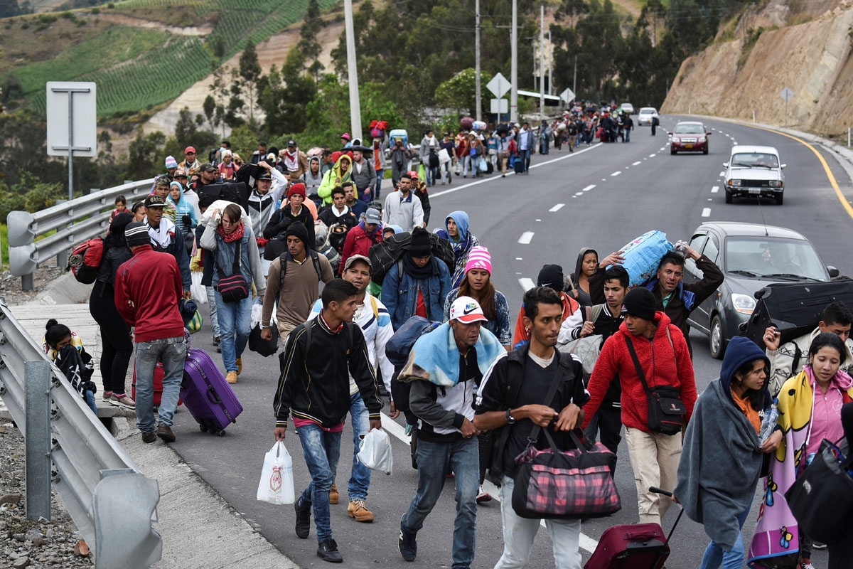 Venezuelan migrants heading to Peru walk along the Pan American highway in Tulcan, Ecuador, after crossing from Colombia, on August 21, 2018.