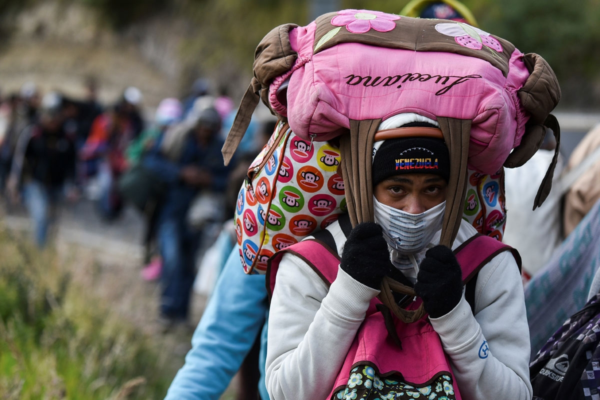 A Venezuelan migrant woman heading to Peru carries bags as she walks along the Pan American highway in Tulcan, Ecuador, after crossing from Colombia, on August 21, 2018.