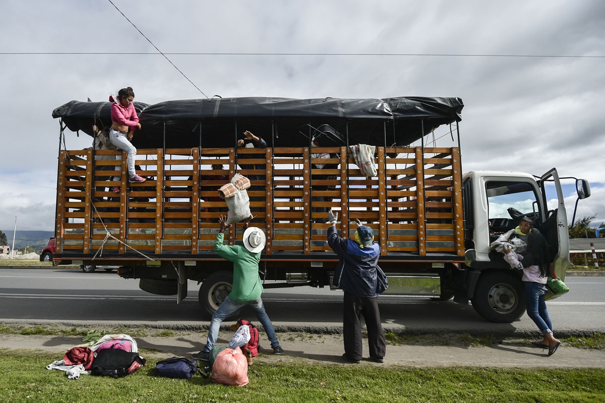 Members of Venezuelan migrant families Mendoza Landinez and Lomelly get off a truck on the Pan-American highway, between Pasto and Ipiales in Colombia, on their way to Peru, on August 23, 2018.