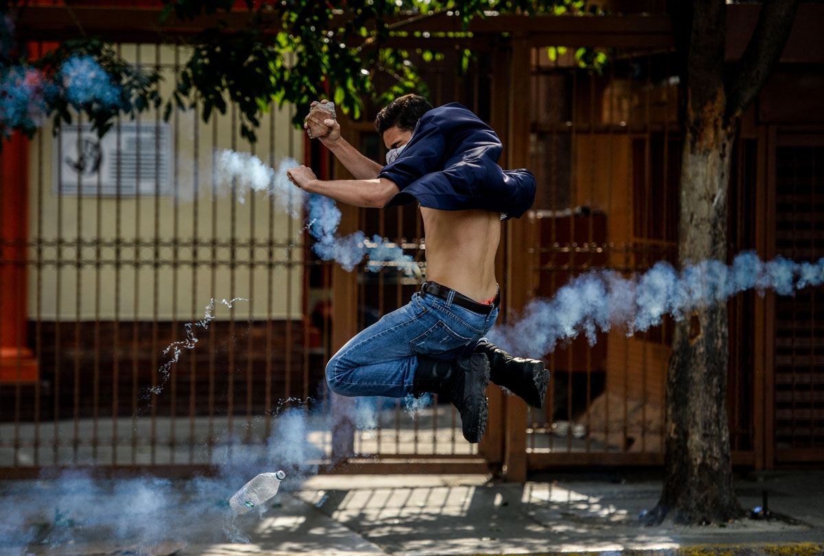 An opposition activist thows a stone at riot police during clashes following a protest against President Nicolas Maduro in Caracas on April 26, 2017.