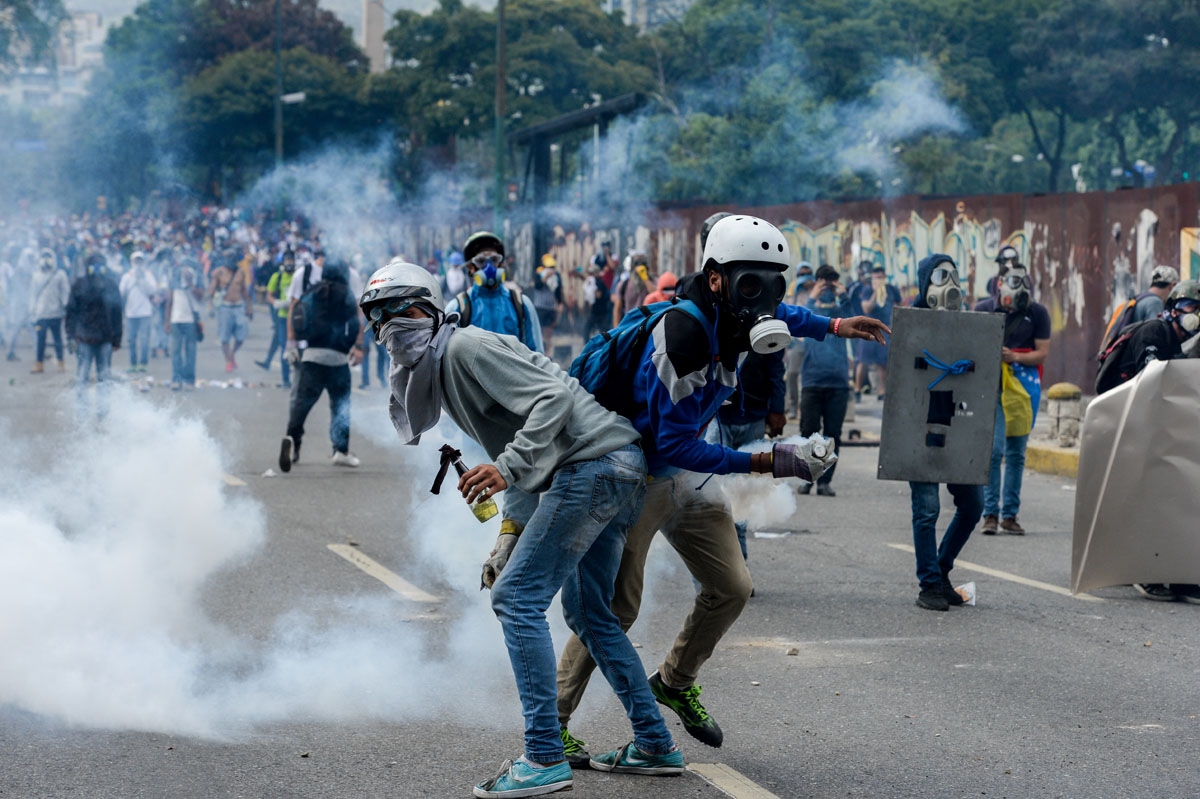 Opposition activists clash with riot police during a protest against President Nicolas Maduro in Caracas on April 26, 2017. Venezuelan riot police fired tear gas to stop anti-government protesters from marching on central Caracas, the latest clash in a w