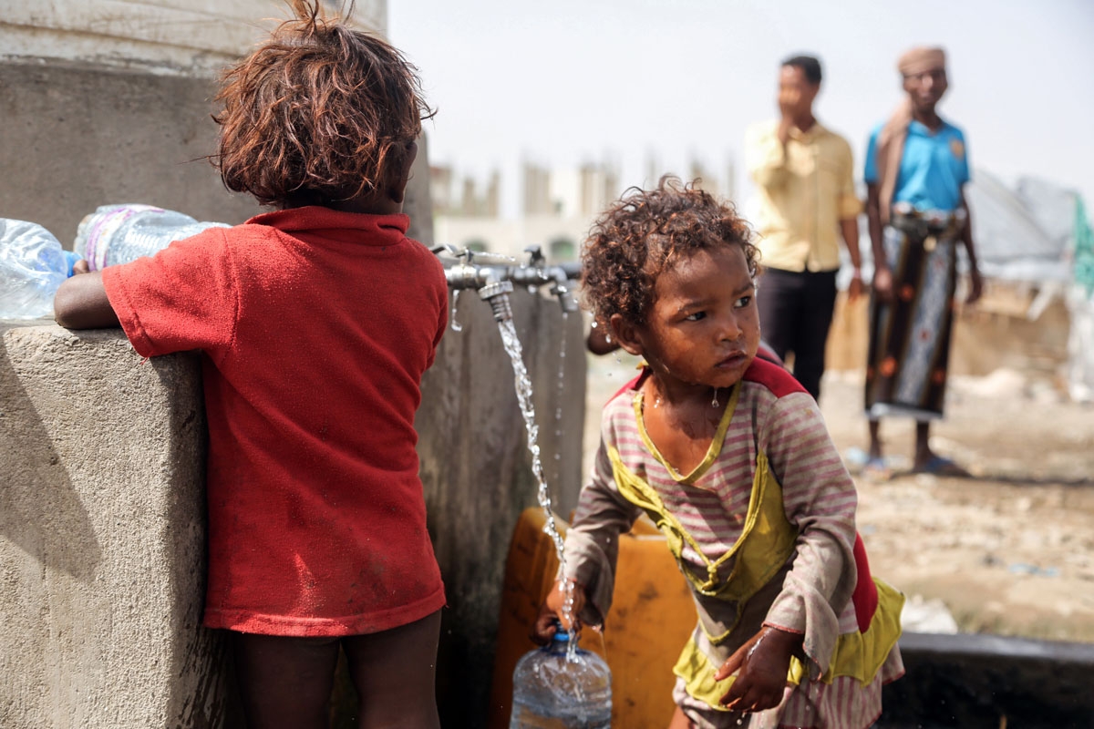 Displaced Yemeni children, who fled fighting between the Saudi-led coalition and Shiite Huthi rebels, fill up carry containers of water from a tap at a camp in the Yemeni coastal city of Hodeidah, on February 17, 2018.