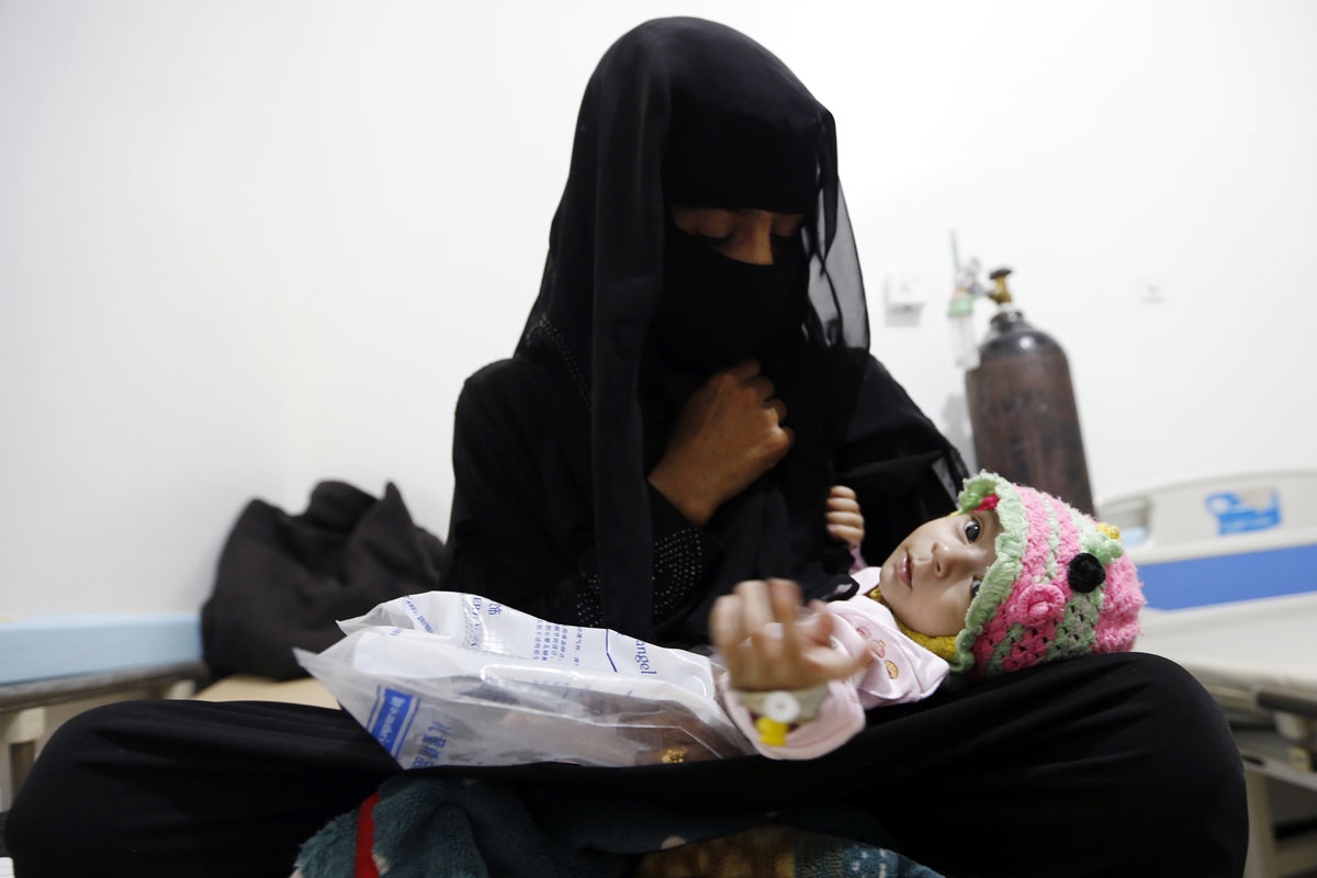 A Yemeni woman holds her child, who is suspected of being infected with cholera, at a makeshift hospital in the capital Sanaa, on August 12, 2017.
