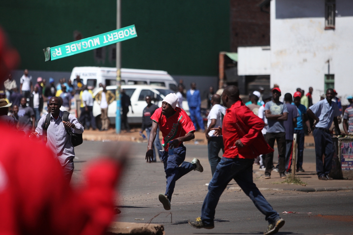 A protester throws a street sign with President Robert Mugabe name on it as Zimbabwe opposition supporters clash with police during a protest march for electoral reforms on August 26, 2016 in Harare.