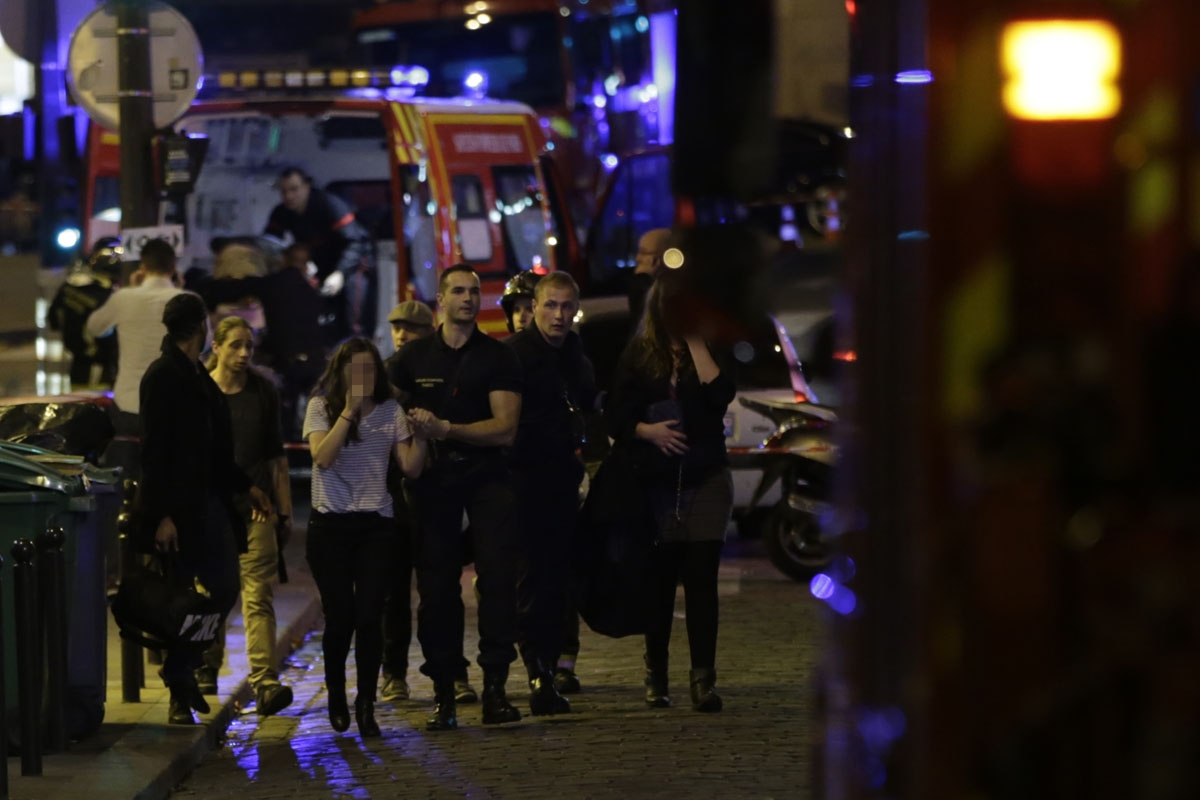 People are evacuated following an attack at the Bataclan concert venue in Paris, on November 13, 2015. At least 18 people were killed in multiple attacks in Paris Friday,