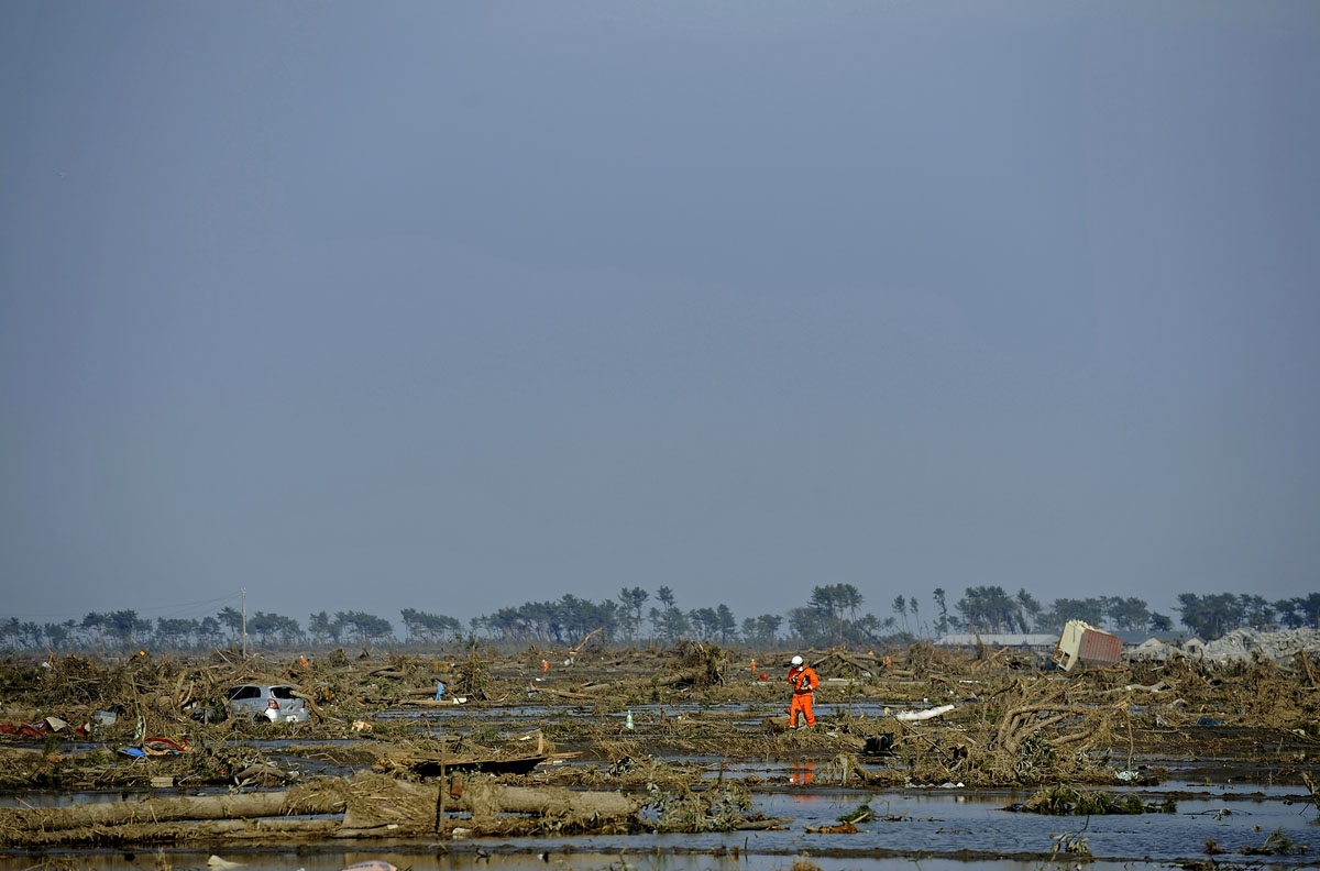 A Japanese rescuer walks across an area devastated by the tsunami in Sendai on March 13, 2011. The massive earthquake and tsunami on March 11 left more than 1,000