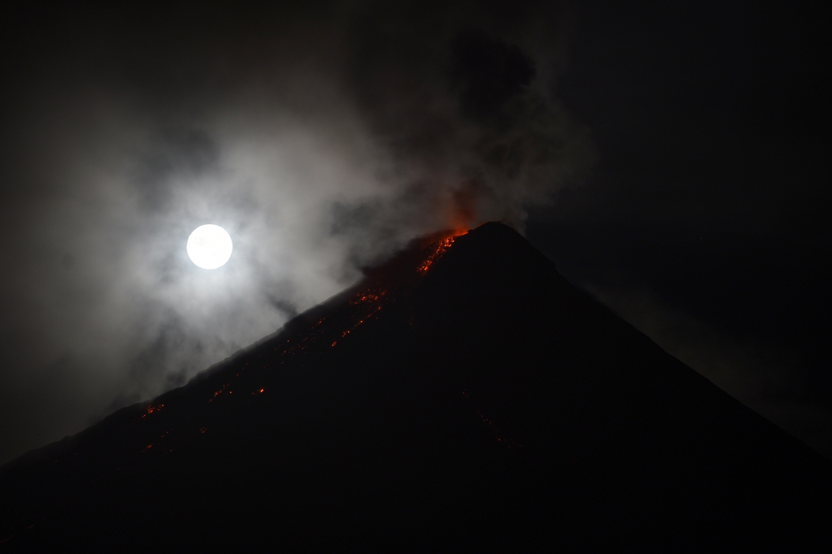 The 'super blue blood moon' obscured by clouds illuminates Mayon volcano as it spews ash near Legazpi City, Albay province, early on February 1, 2018.