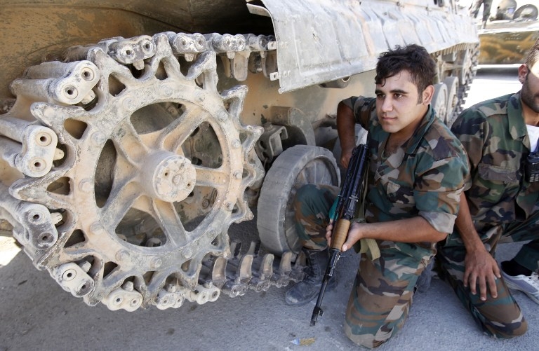 Des soldats syriens s'abritent derrière un blindé dans une rue de Maaloula Des soldats syriens s'abritent derrière un blindé dans une rue de Maaloula