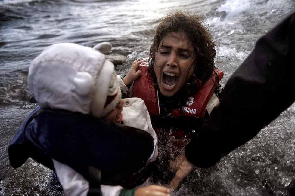 Une femme tombe à l'eau avec son enfant sur une plage de Lesbos après avoir traversé la mer Égée depuis la Turquie, en octobre. (AFP/Aris Messinis) Une femme tombe à l'eau avec son enfant sur une plage de Lesbos après avoir traversé la mer Égée depuis la Turquie, en octobre. (AFP/Aris Messinis)