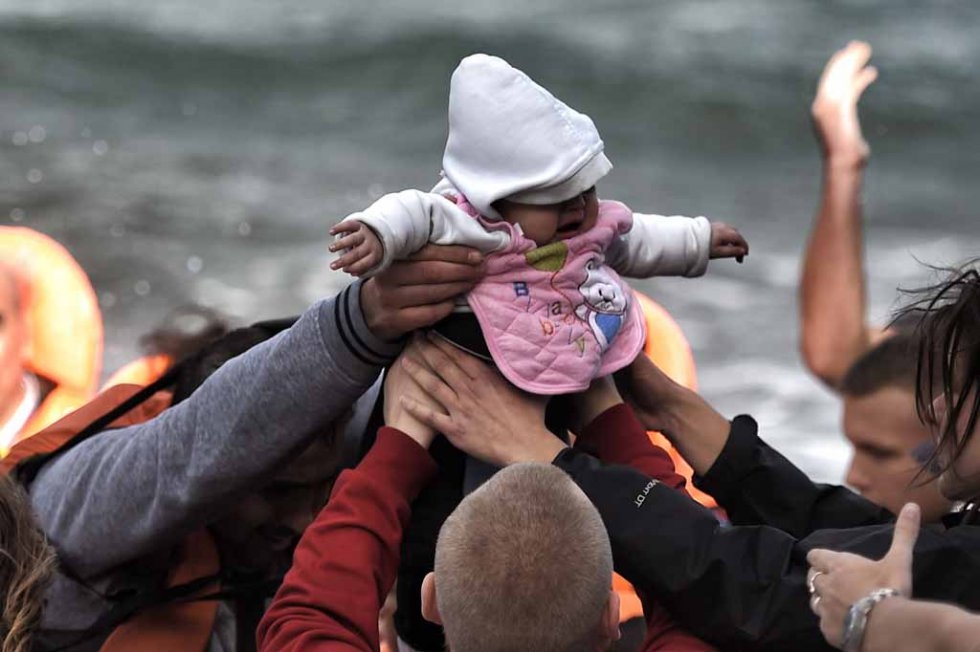 Un bébé passe de main en main à son arrivée à Lesbos, fin octobre. Un bébé passe de main en main à son arrivée à Lesbos, fin octobre.