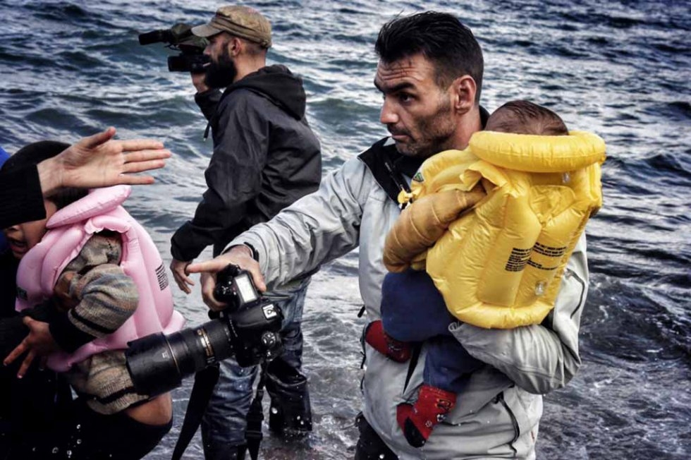 Aris Messinis transporte un enfant sur le rivage à Lesbos. (Photo Aris Messinis transporte un enfant sur le rivage à Lesbos. (Photo