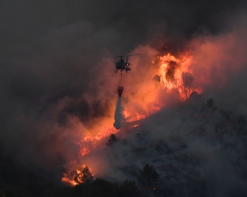 An helicopter carries an extinguisher in the struggle against a fire that spread near Vitrolles, southern France on August 10, 2016