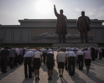 People bow as they pay their respects to the statues of former North Korean leaders Kim Il-Sung and Kim Jong-Il, at Mansu hill in Pyongyang on July 7, 2016
