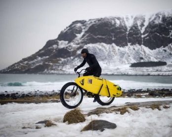 Australian surf legend from the 80's Tom Carroll, 55, rides a bike in Unstad on March 9, 2017 before surfing the Arctic waves of the Atlantic Ocean. / AFP PHOTO / OLIVIER MORIN