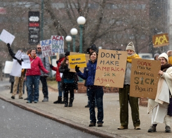 Demonstartors hold signs in the snow during a rally in support of the Affordable Care Act (ACA) in Denver, Colorado on January 15, 2017. - President-elect Donald Trump and his Republican allies have vowed a swift repeal of President Barack Obama's landmar
