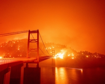 A boat motors by as the Bidwell Bar Bridge is surrounded by fire in Lake Oroville during the Bear fire in Oroville, California on September 9, 2020. - Dangerous dry winds whipped up California's record-breaking wildfires and ignited new blazes Tuesday, as