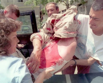 Un journaliste (à droite) et un passant viennent en aide à un chauffeur de bus grièvement blessé par un obus de mortier dans le centre de Sarajevo, le 15 juin 1995 (AFP / Anja Niedringhaus)