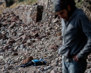 A man stands next to the body of a migrant child washed up on a beach in Canakkale's Bademli district on January 30, 2016